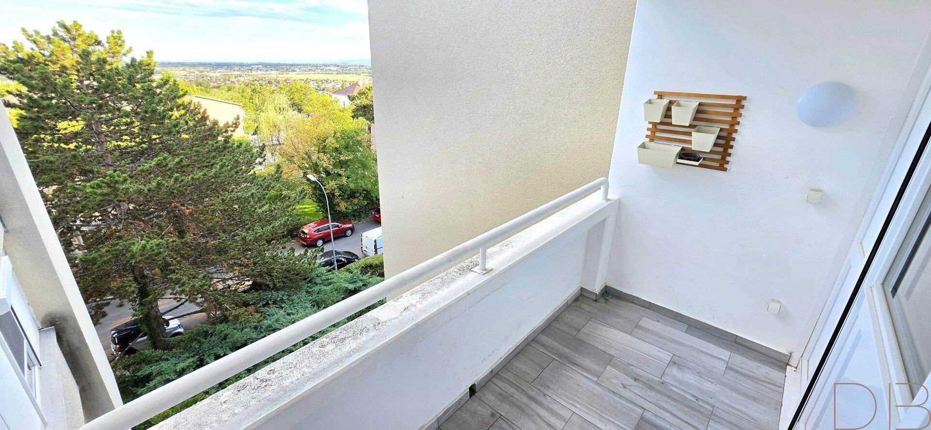 Geräumiger Balkon mit Fliesenboden und weitem Blick über die Baumwipfel.