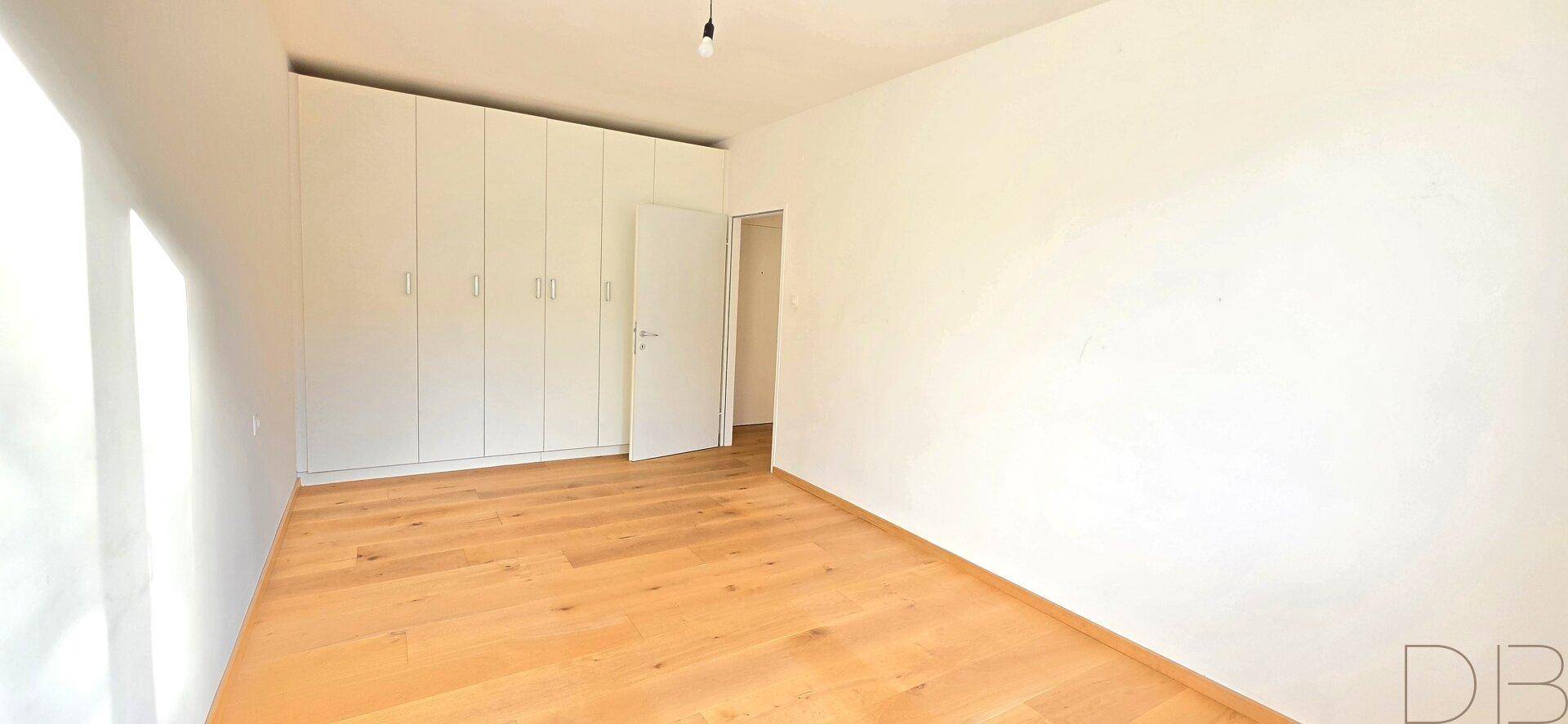 Helles Schlafzimmer mit Einbauschränken und hochwertigem Holzboden.