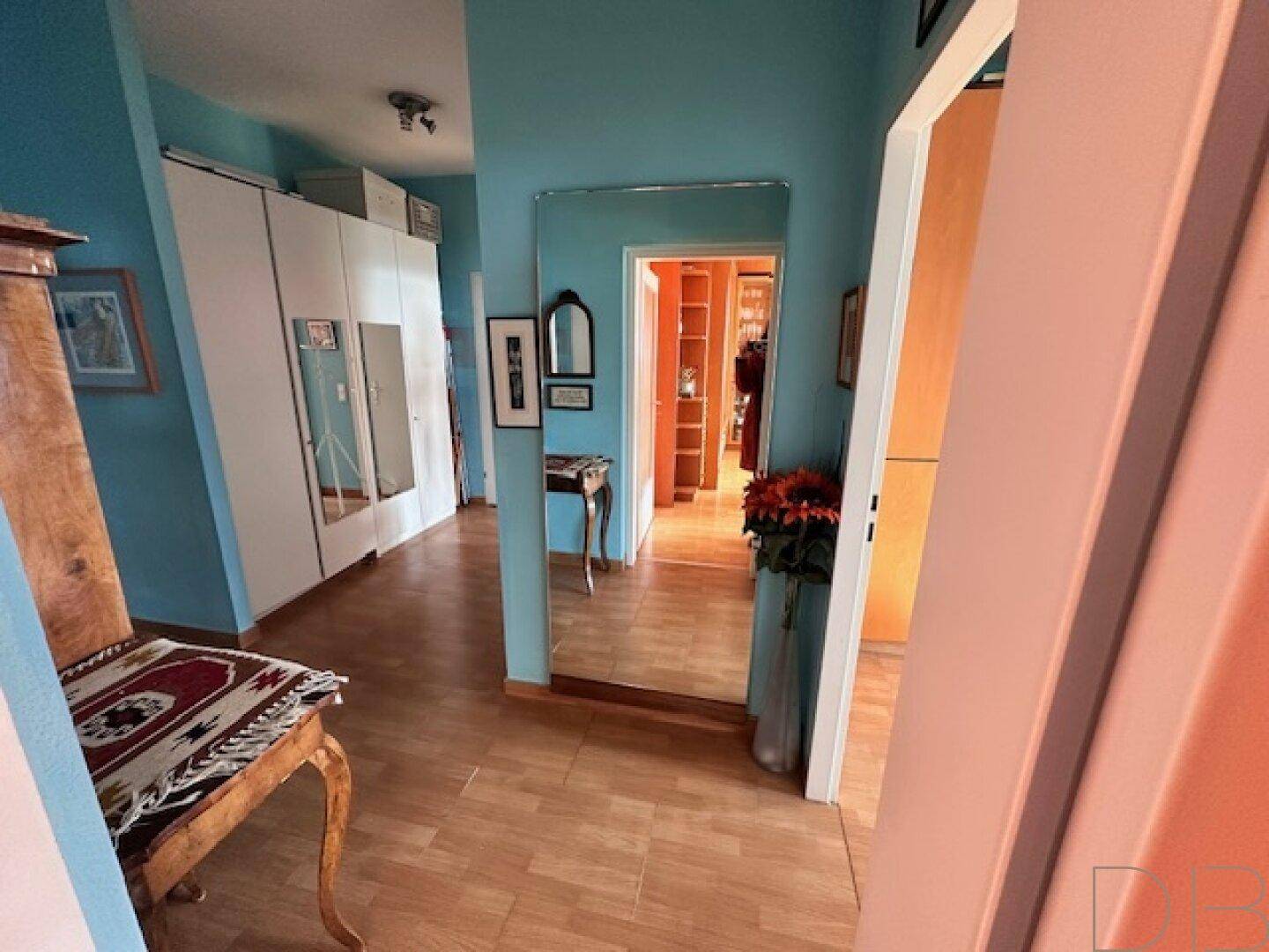 Geräumiger Flur mit blauen Wänden, Holzfußboden, großem Spiegel und Einbauschränken.