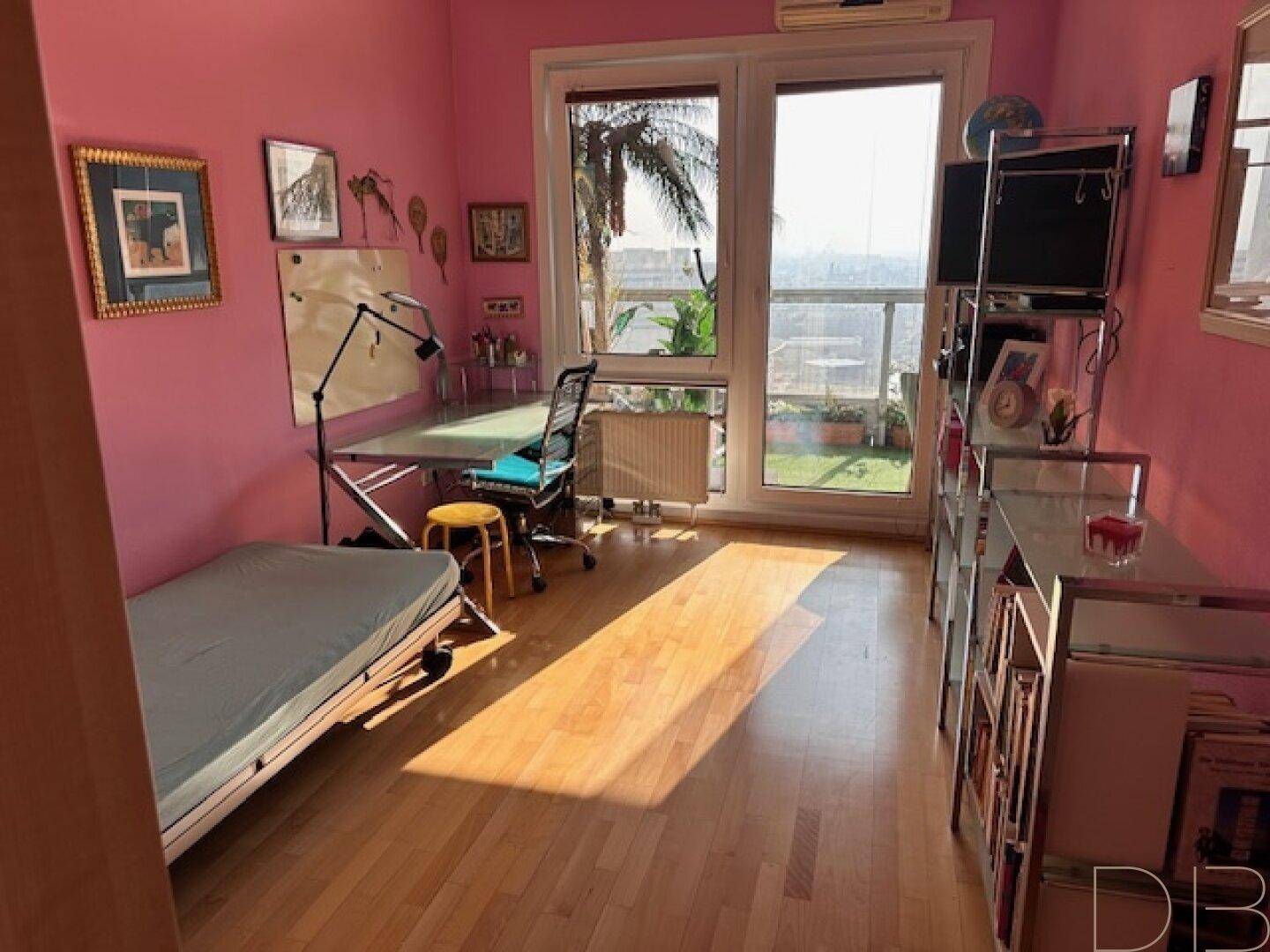 Helles Zimmer mit rosa Wänden, Schreibtisch, Einzelbett und großem Fenster mit Blick ins Grüne.