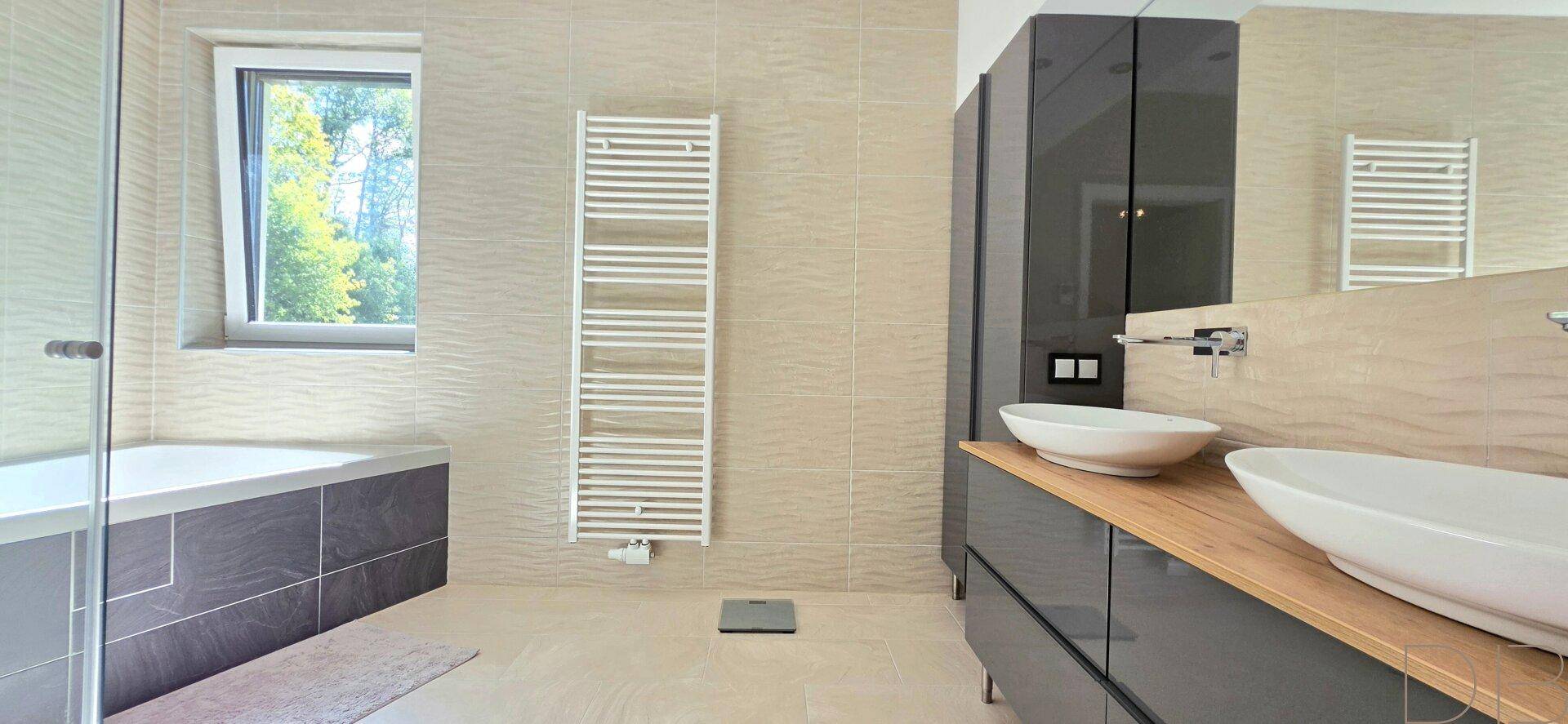 Modernes Badezimmer mit Doppelwaschbecken, Badewanne und beheiztem Handtuchhalter.