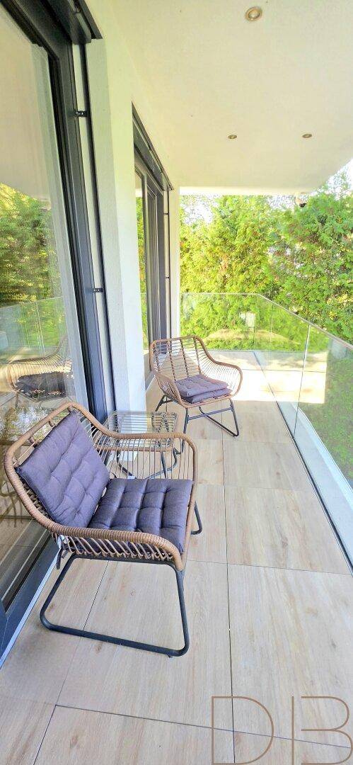 Gemütlicher Balkon mit Rattanmöbeln und Blick auf die grüne Umgebung.