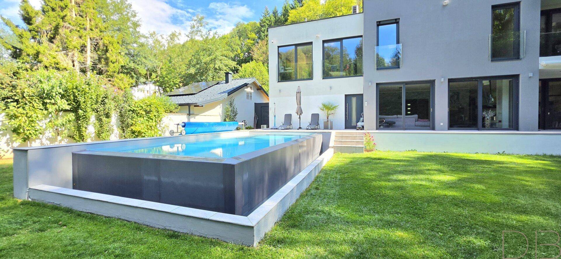 Moderner Swimmingpool im Gartenbereich mit angrenzender Terrasse und Blick auf das Haus.