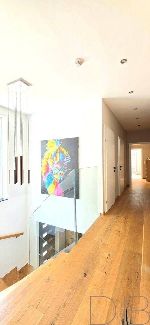 Heller Flur im Obergeschoss mit Holzboden, Kunstwerk und Blick auf die Treppe.