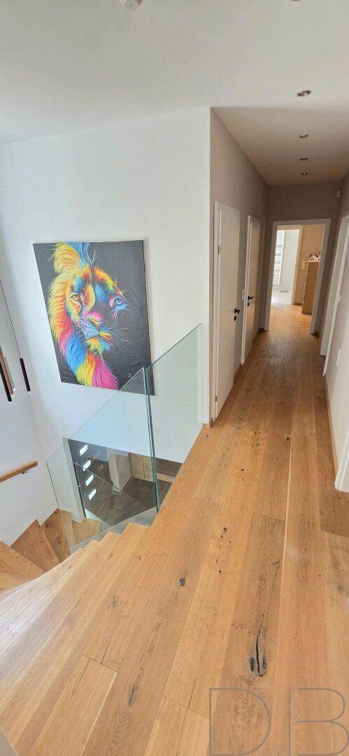 Heller Flur im Obergeschoss mit Holzboden, Kunstwerk und Blick auf die Treppe.