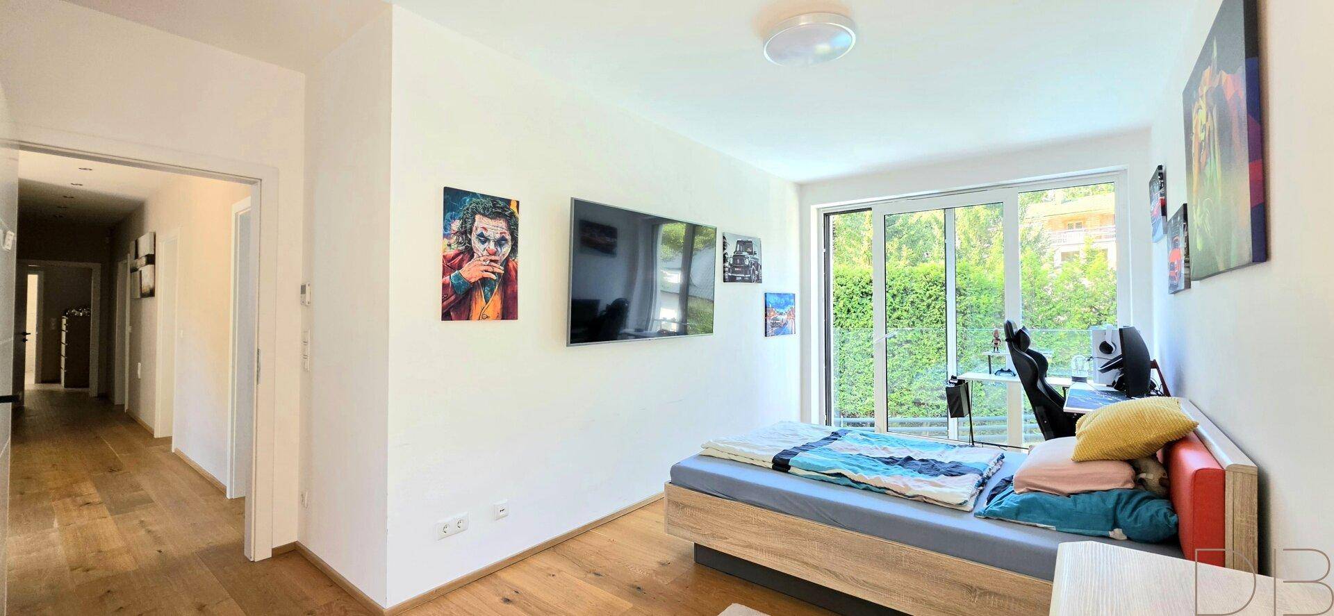 Helles Schlafzimmer mit Holzboden, großem Fenster und Zugang zu einem Balkon.