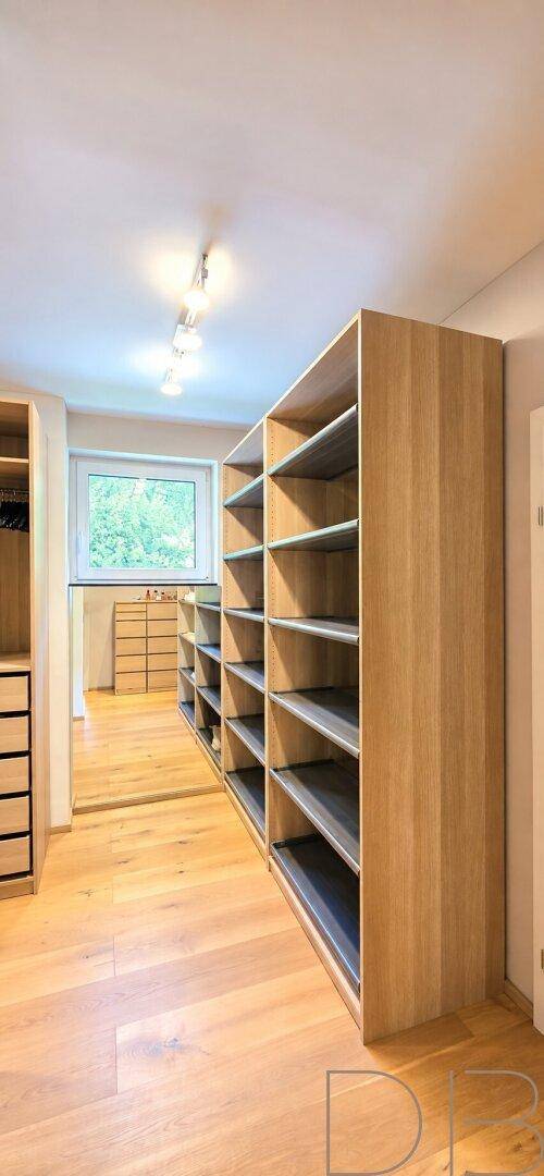 Geräumiger begehbarer Kleiderschrank mit offenen Regalen und Fenster für Tageslicht.