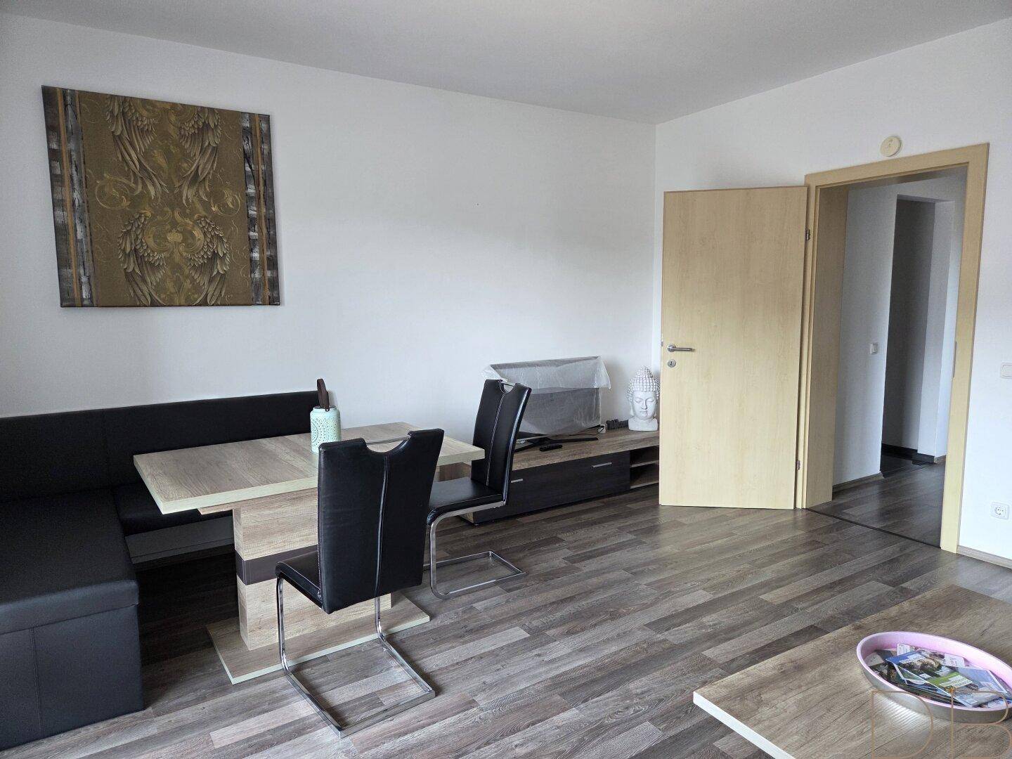 Gemütlicher Wohn- und Essbereich mit Holzboden, Esstisch und Sofa.