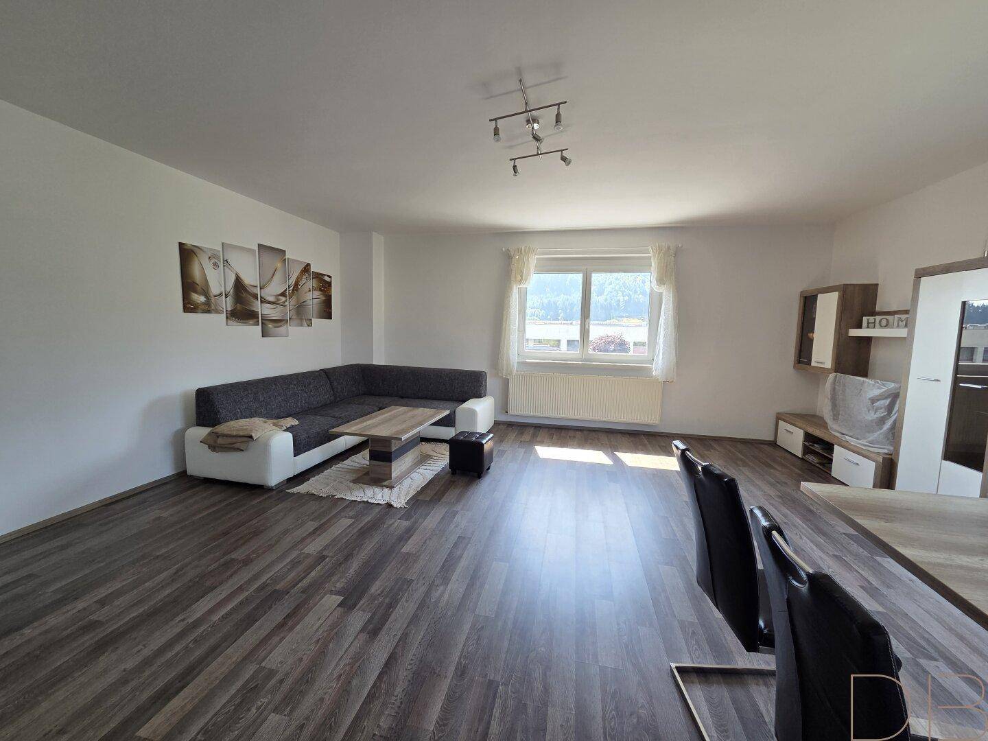 Geräumiger Wohn- und Essbereich mit L-förmigem Sofa und Holzboden.