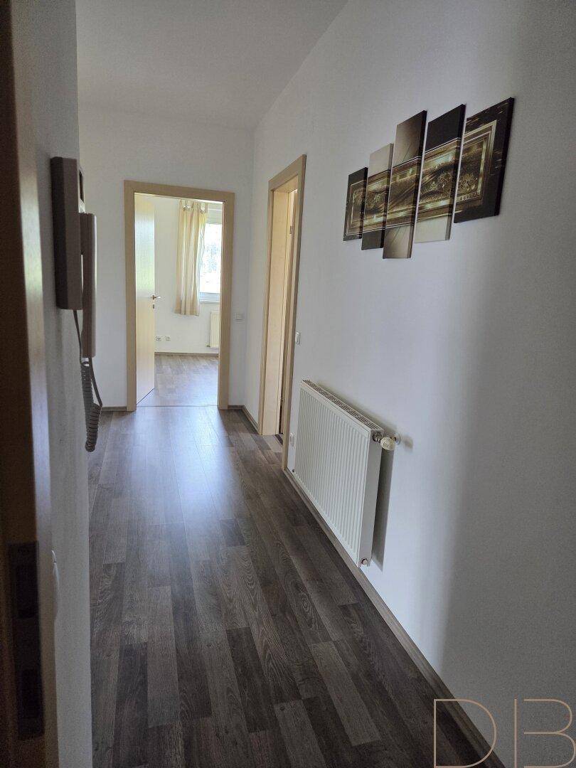 Heller Flur mit Holzboden und Zugang zu weiteren Räumen.