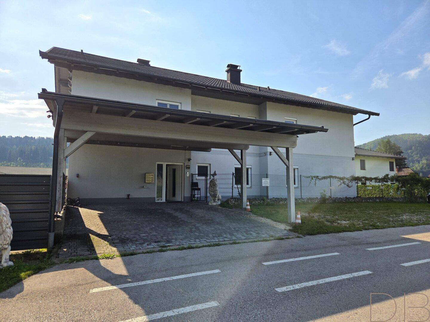 Vorderansicht des Hauses mit Carport und gepflasterter Zufahrt.