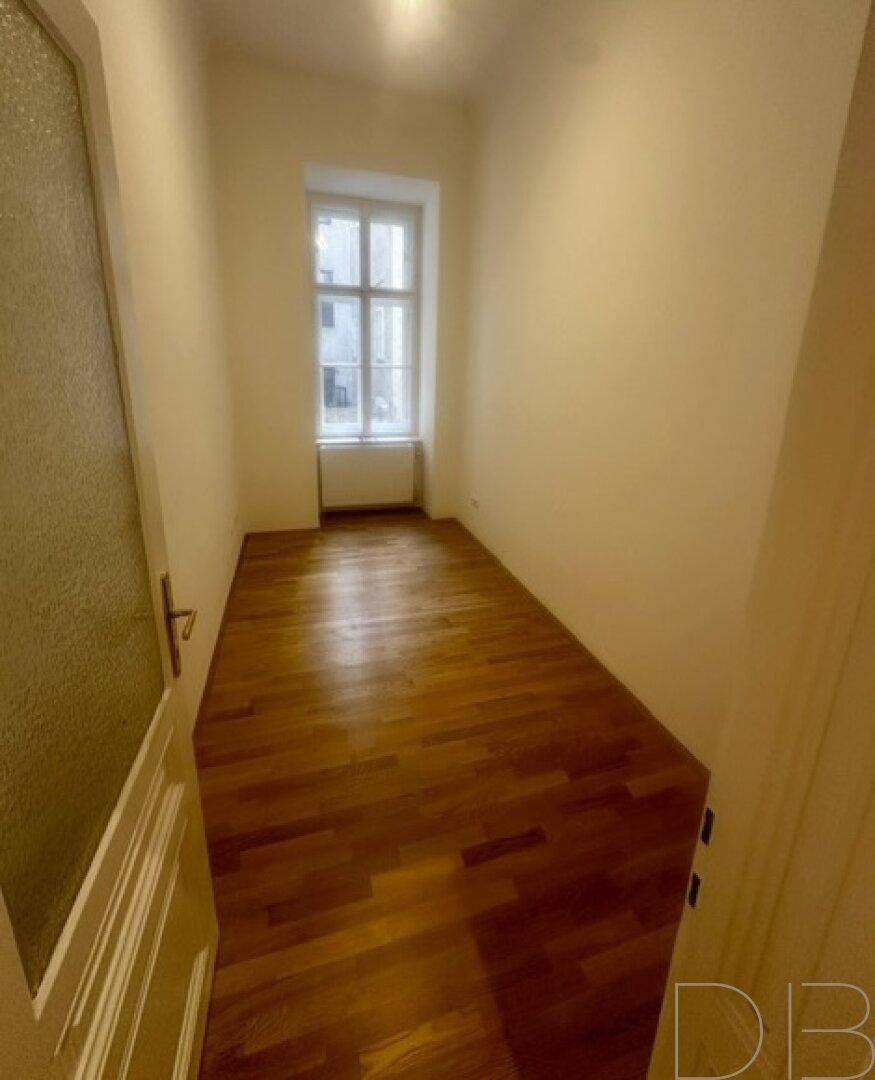 Kleines, helles Zimmer mit Parkettboden und einem Fenster, ideal als Arbeits- oder Schlafzimmer.