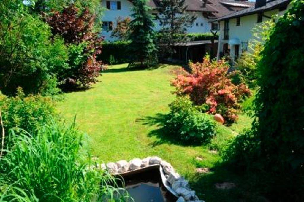 Großer, gepflegter Garten mit Rasenfläche, Bäumen und einem kleinen Teich.