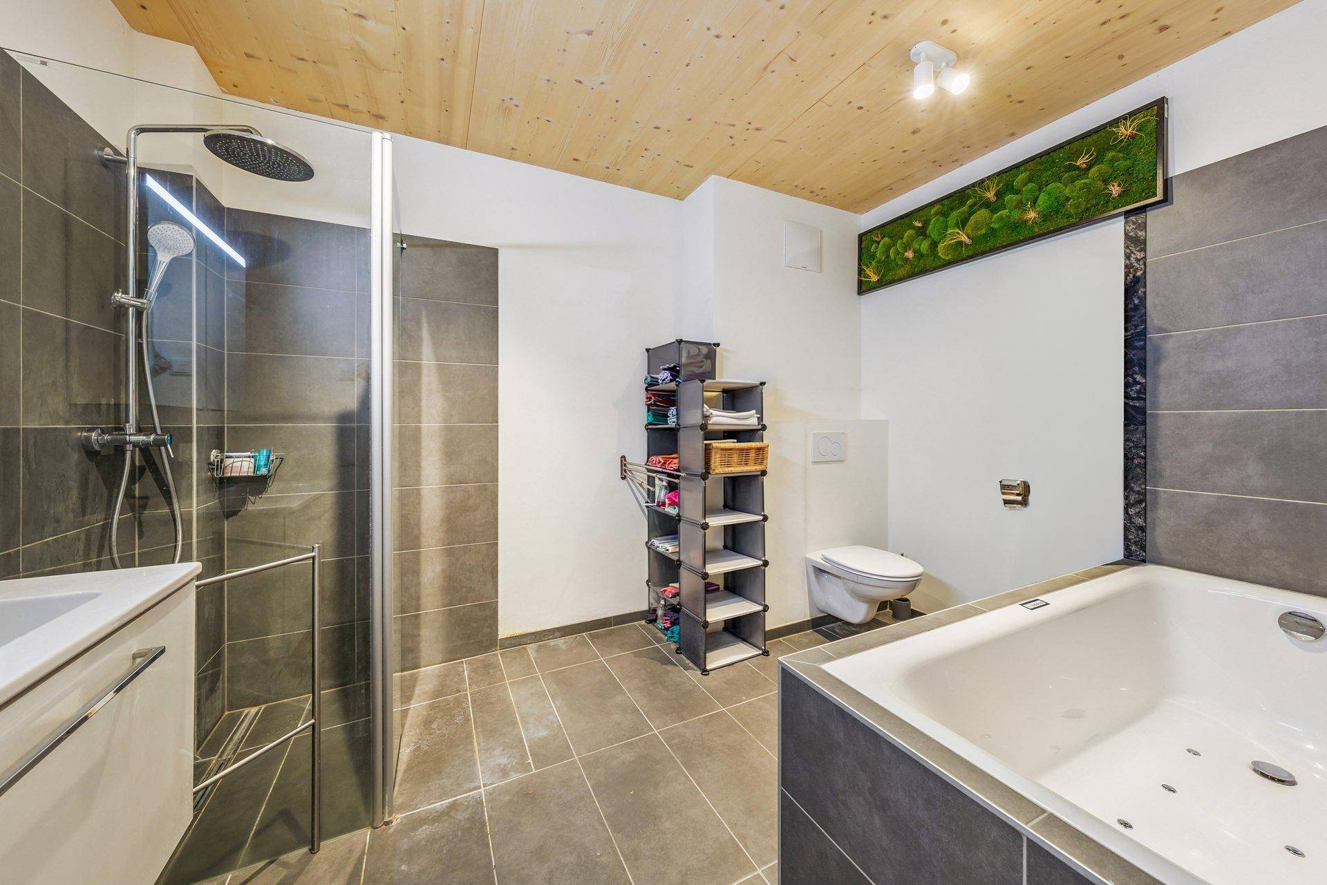 Modernes Badezimmer mit großer Dusche, Badewanne und stilvoller Mooswanddekoration.
