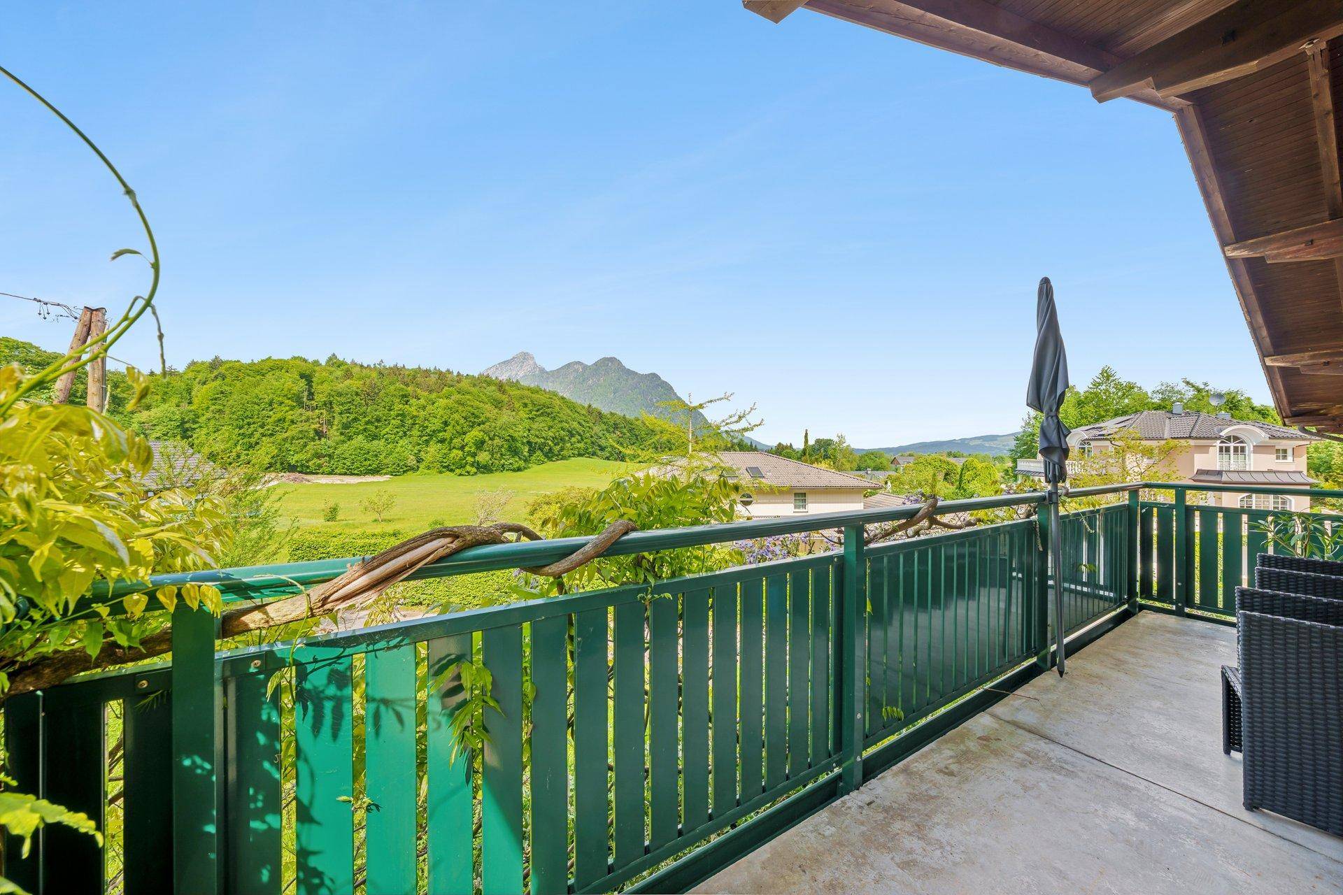 Balkon mit grüner Brüstung und weitem Blick auf die umliegende Berglandschaft.