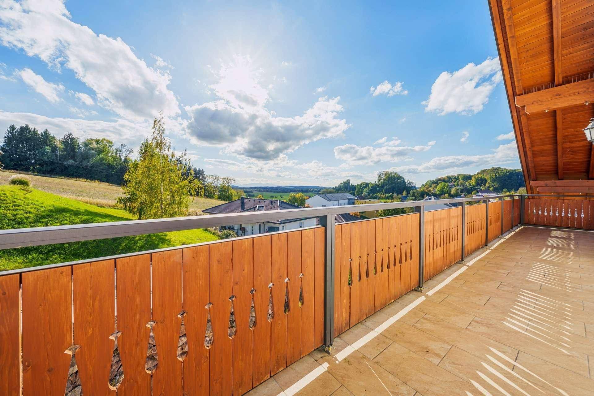 Sonniger Balkon mit Holzbalkonbrüstung und weitem Blick über die Landschaft.
