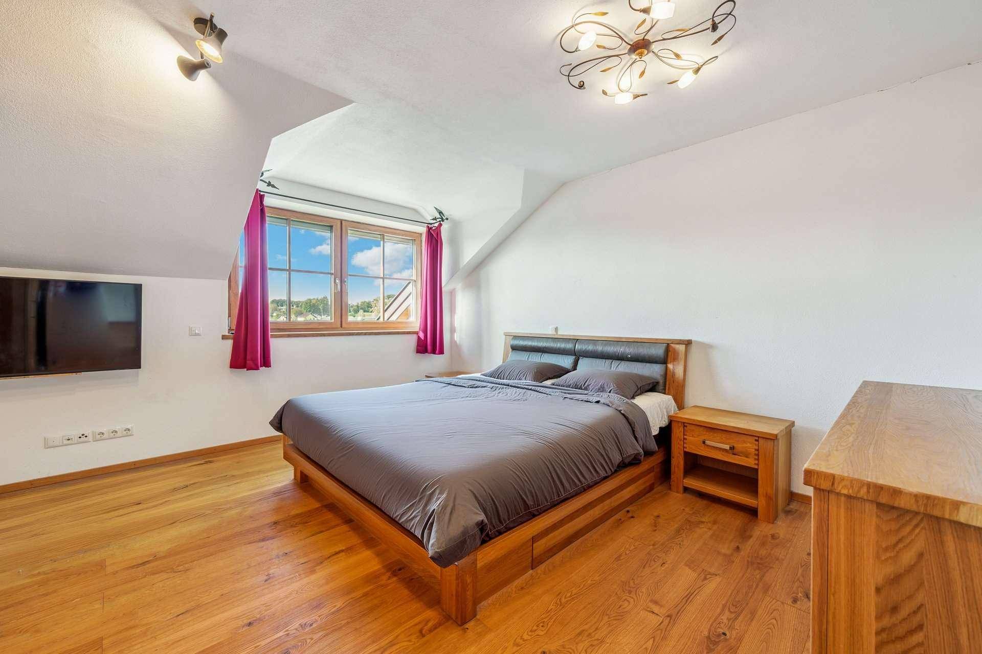 Schlafzimmer mit Holzbett, Holzboden und Dachschrägenfenster für viel Licht.