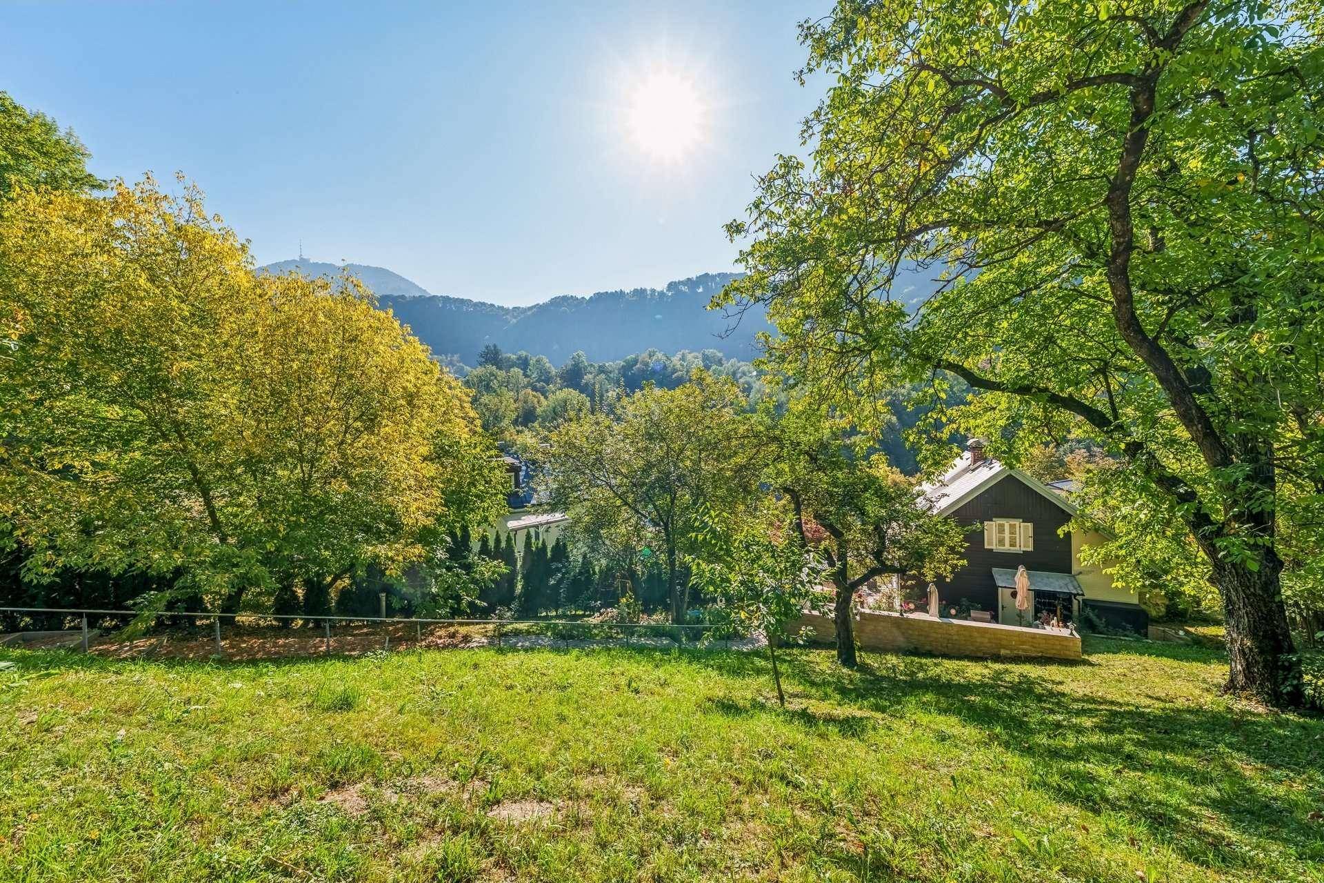 Großer Garten mit Rasenfläche, altem Baumbestand und weitem Blick auf die Hügellandschaft.