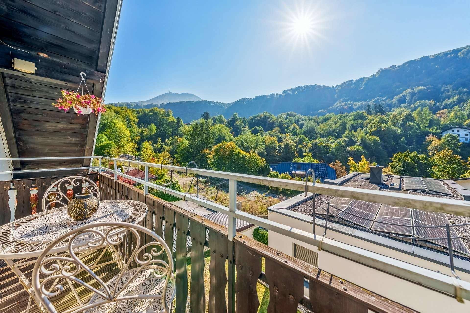 Sonniger Balkon mit Sitzgelegenheiten und weitem Blick auf die umliegende Berglandschaft.