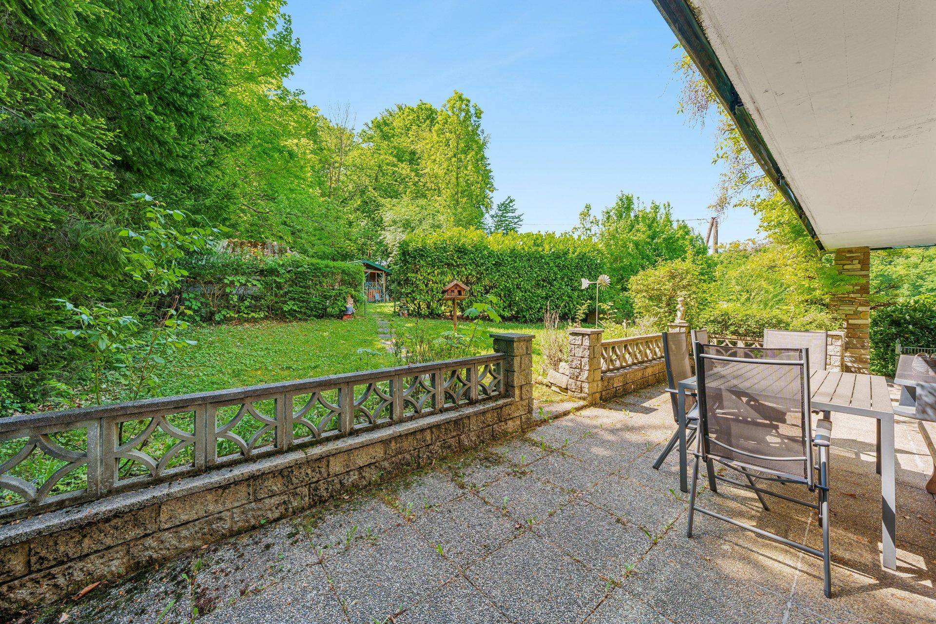Gepflasterte Terrasse mit Gartenmöbeln und Blick auf den grünen Gartenbereich.