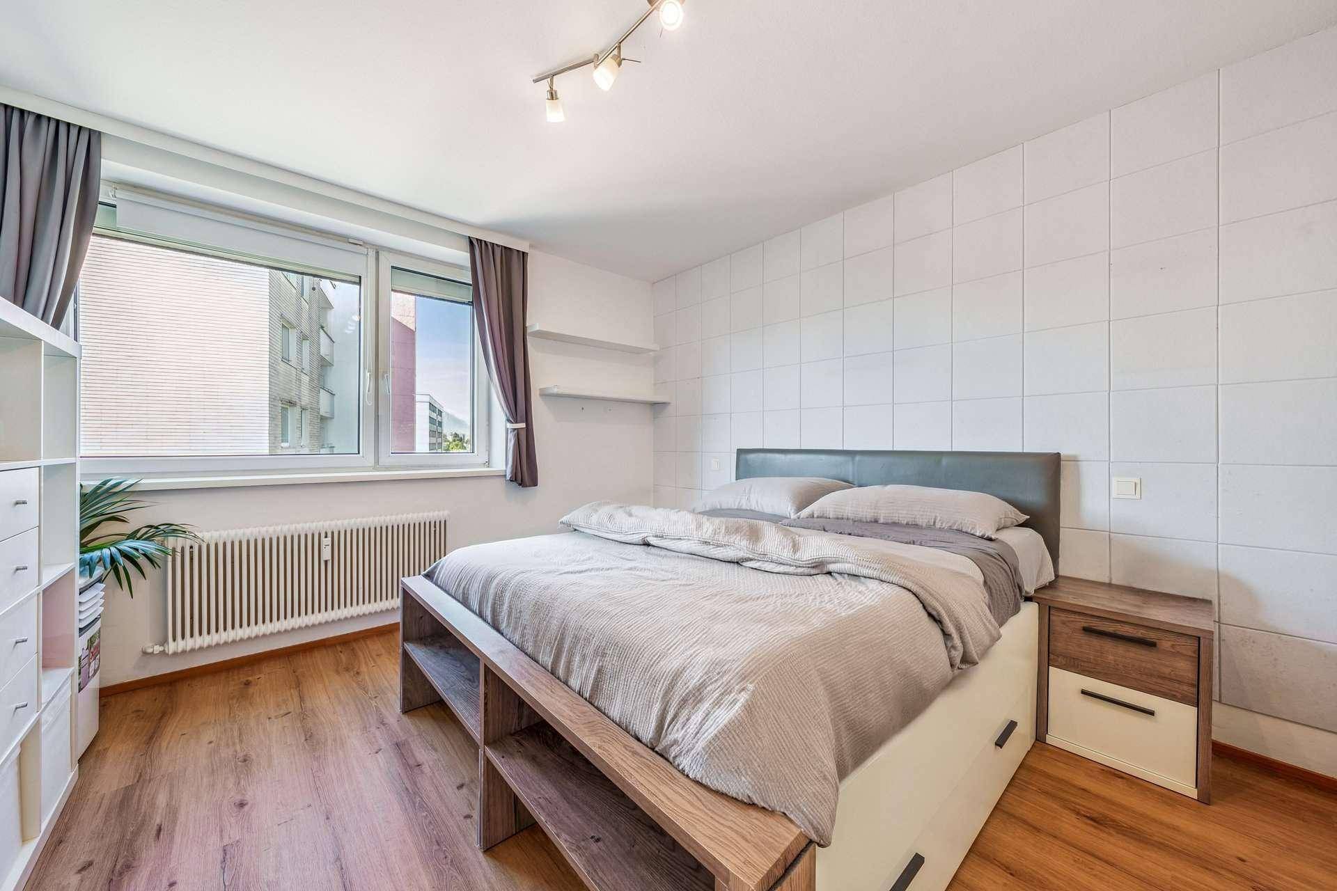 Helles Schlafzimmer mit Holzboden, Doppelbett und einem großen Fenster für viel Tageslicht.