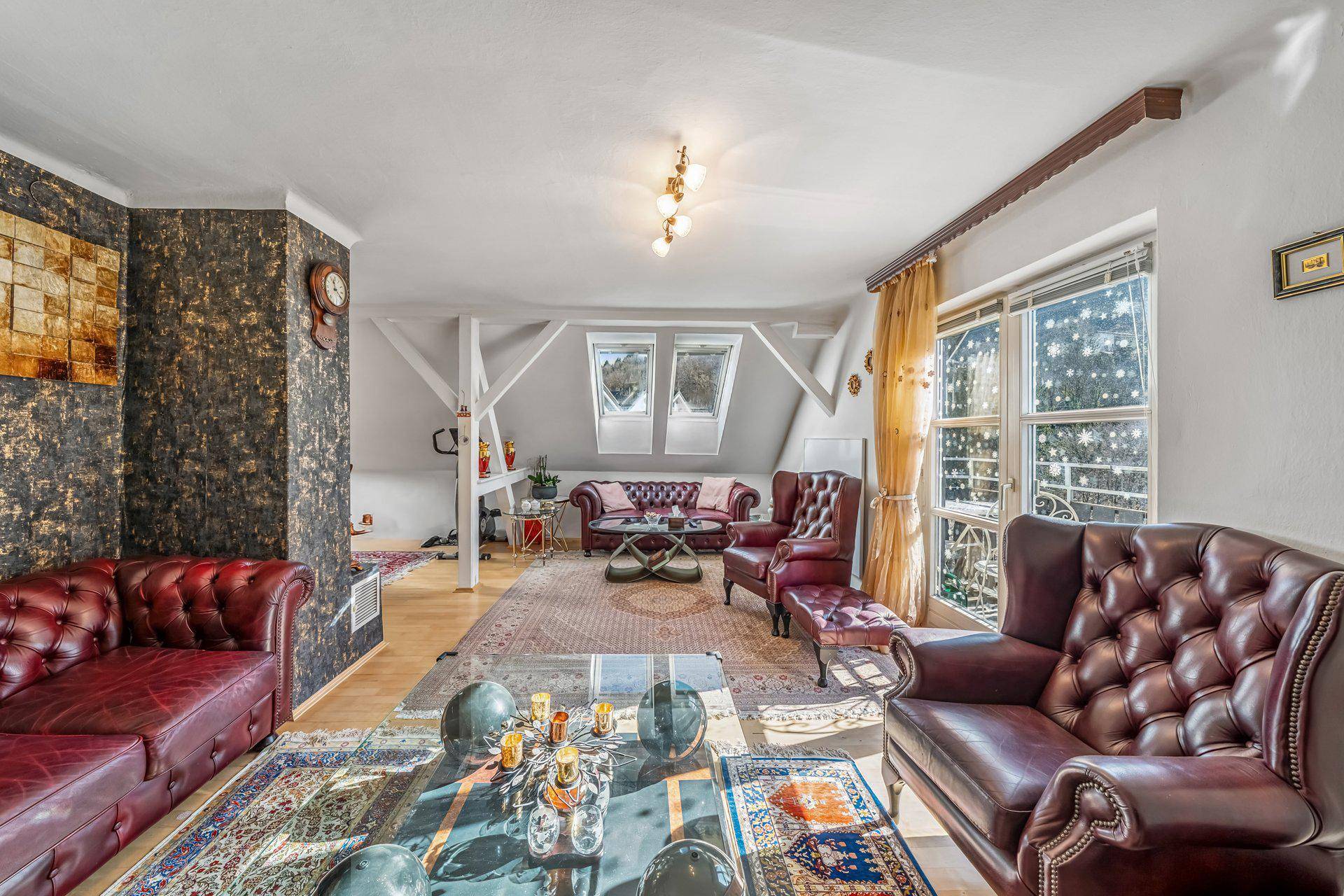 Geräumiges Wohnzimmer im Dachgeschoss mit Ledermöbeln, Holzboden und Dachfenstern für viel Licht.
