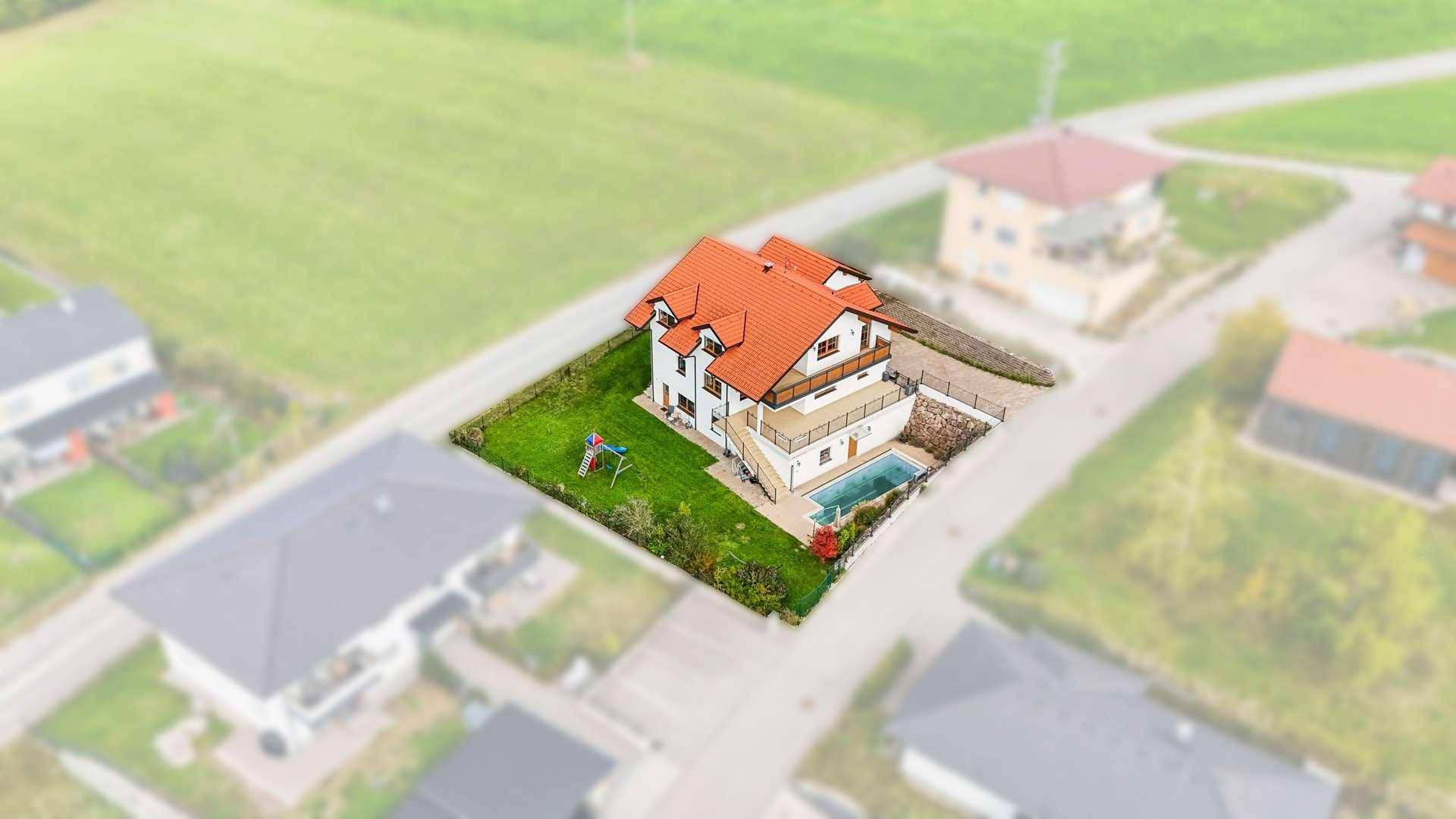 Luftaufnahme des Einfamilienhauses mit Grundstück, Pool und umliegender Bebauung.