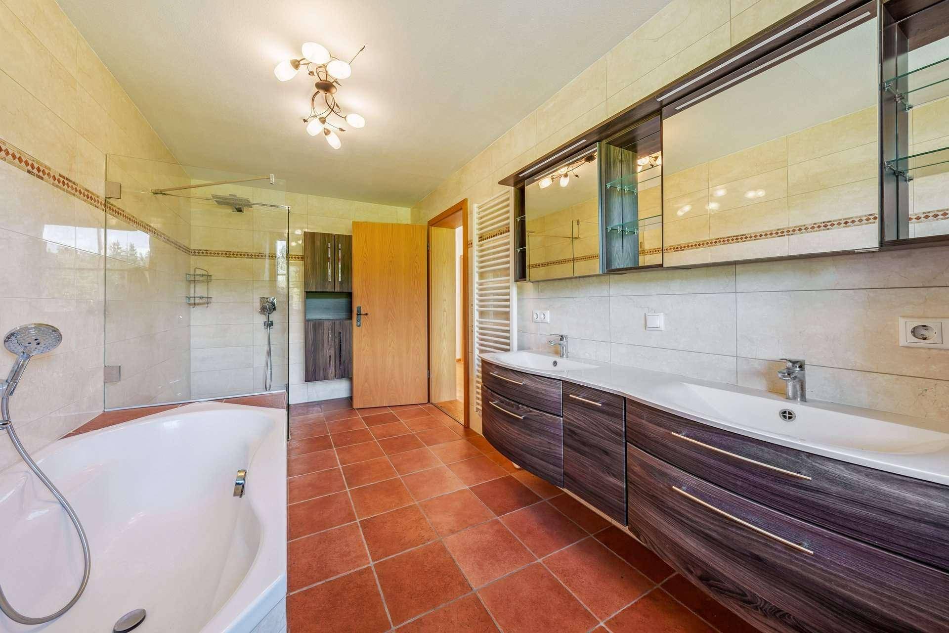 Geräumiges Badezimmer mit Badewanne, Dusche, Doppelwaschbecken und Fliesenboden.