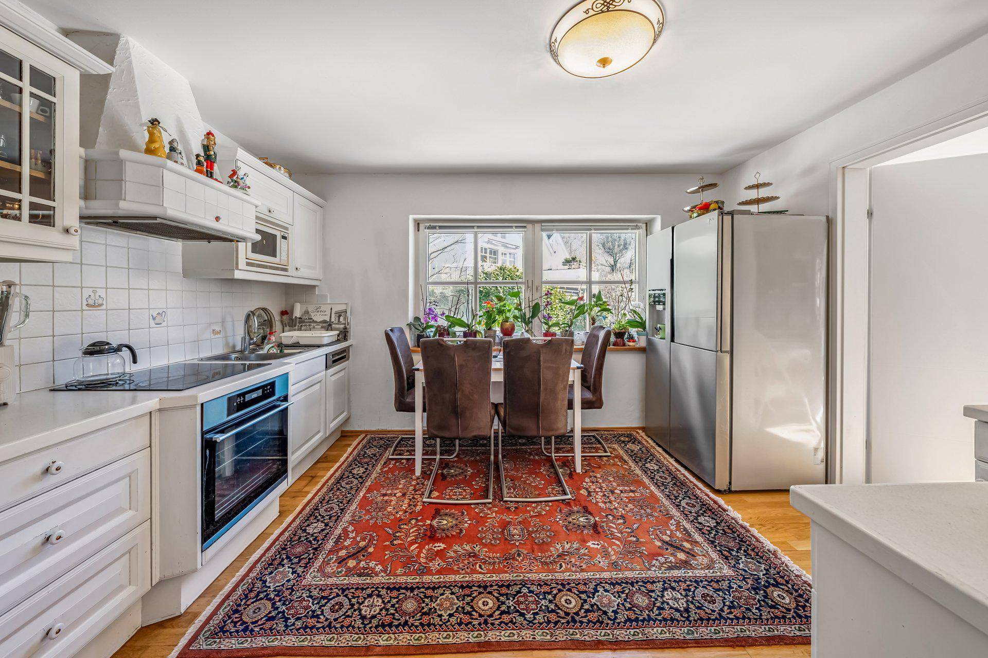 Helle Wohnküche mit Einbaumöbeln, Esstisch und Fenster mit Blick ins Grüne.