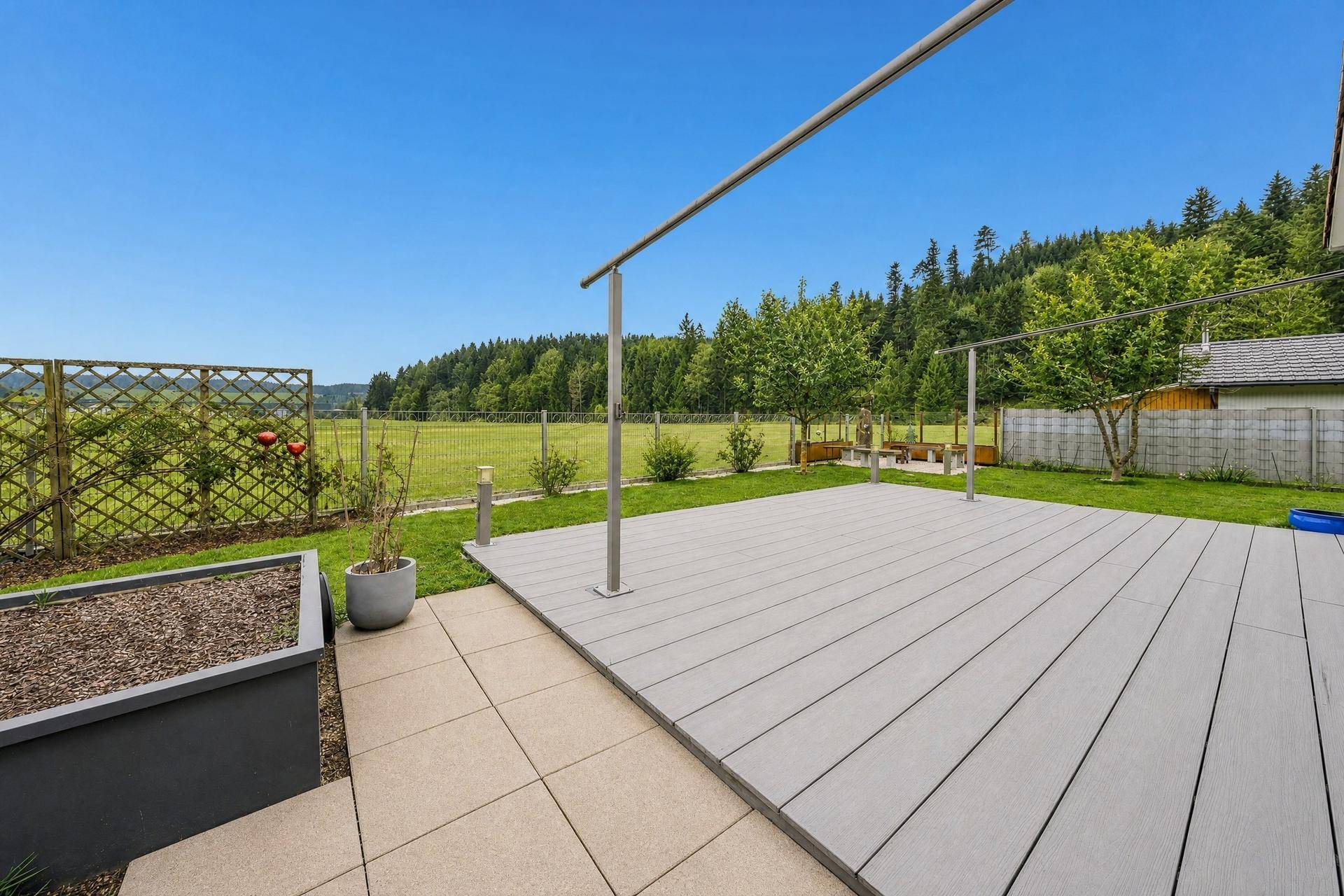 Geräumige Terrasse mit Pergola und weitem Blick über die grüne Landschaft.