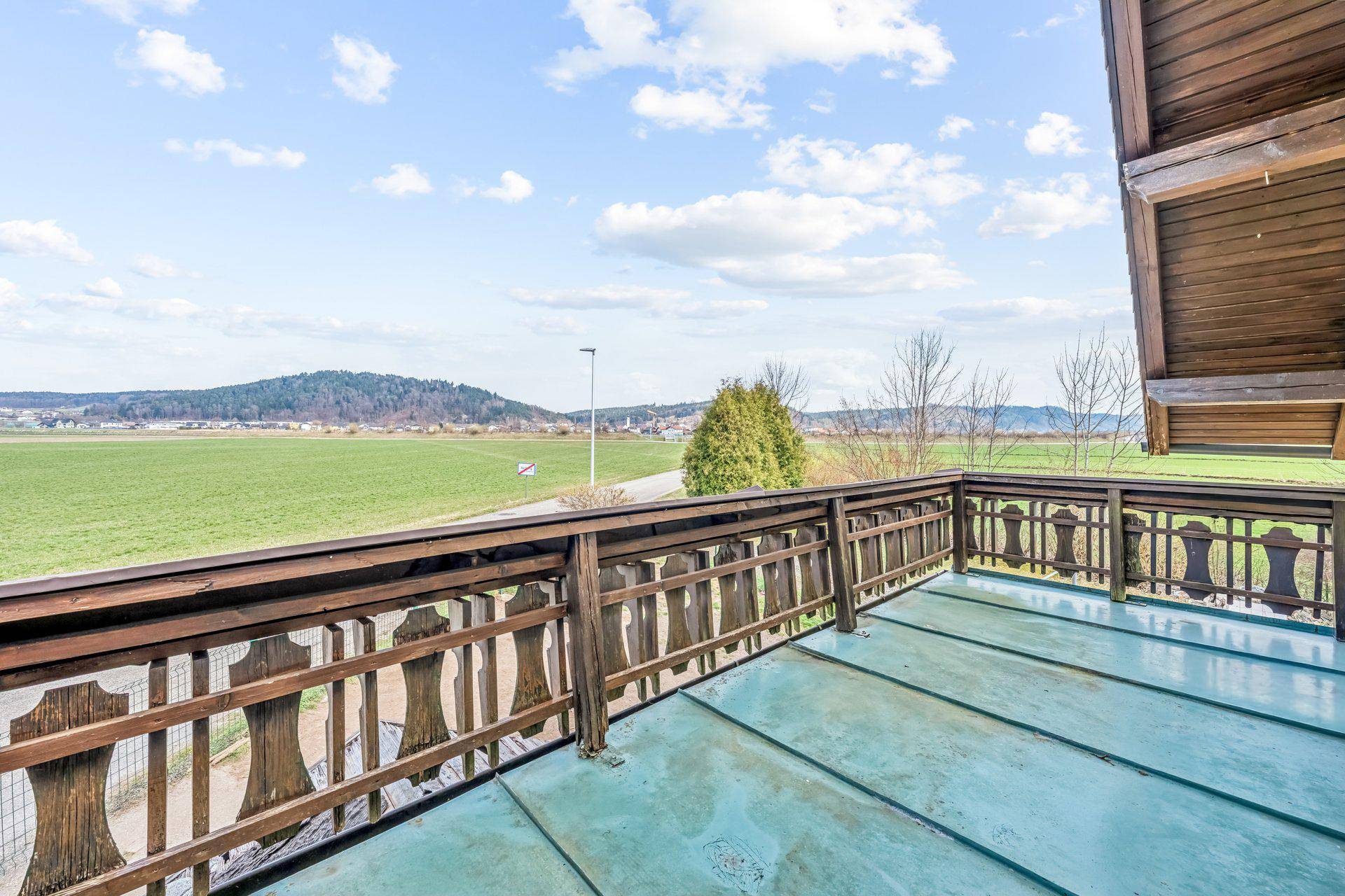 Traditioneller Holzbalkon mit weitem Blick über grüne Felder und die umliegende Landschaft.