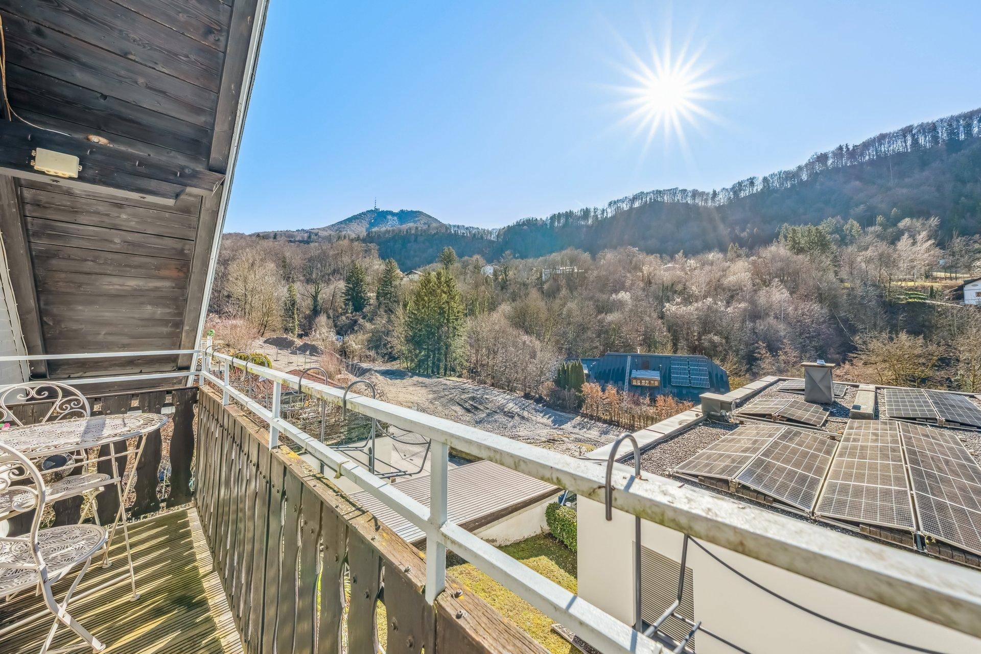 Sonniger Balkon mit Sitzgelegenheiten und herrlichem Blick auf die Berge und die umliegende Natur.