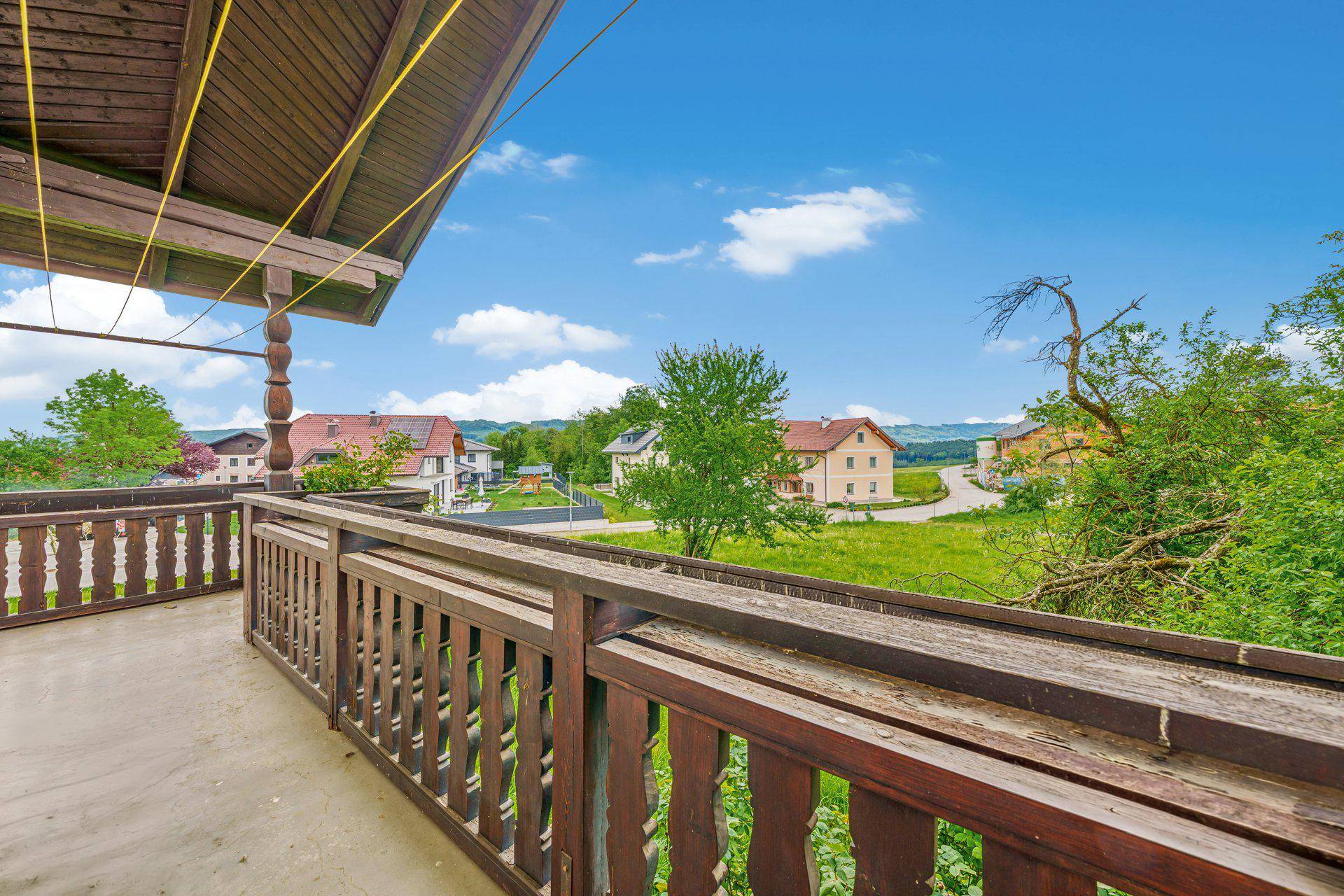Holzbalkon mit traditionellem Geländer und weitem Blick über die grüne Hügellandschaft.
