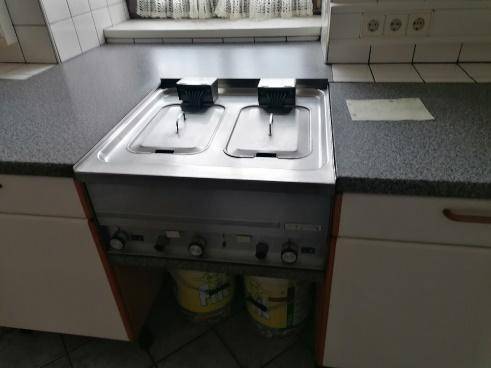 Professionelle Küche mit zwei Fritteusen und Arbeitsflächen, bereit für den Gastronomiebetrieb.