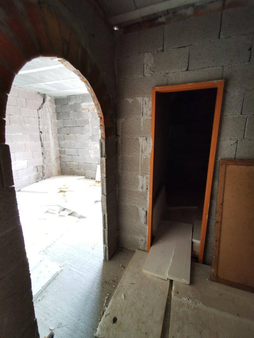 Rohbau mit Ziegelwänden und einem gemauerten Bogen, der auf weitere Bauarbeiten wartet.