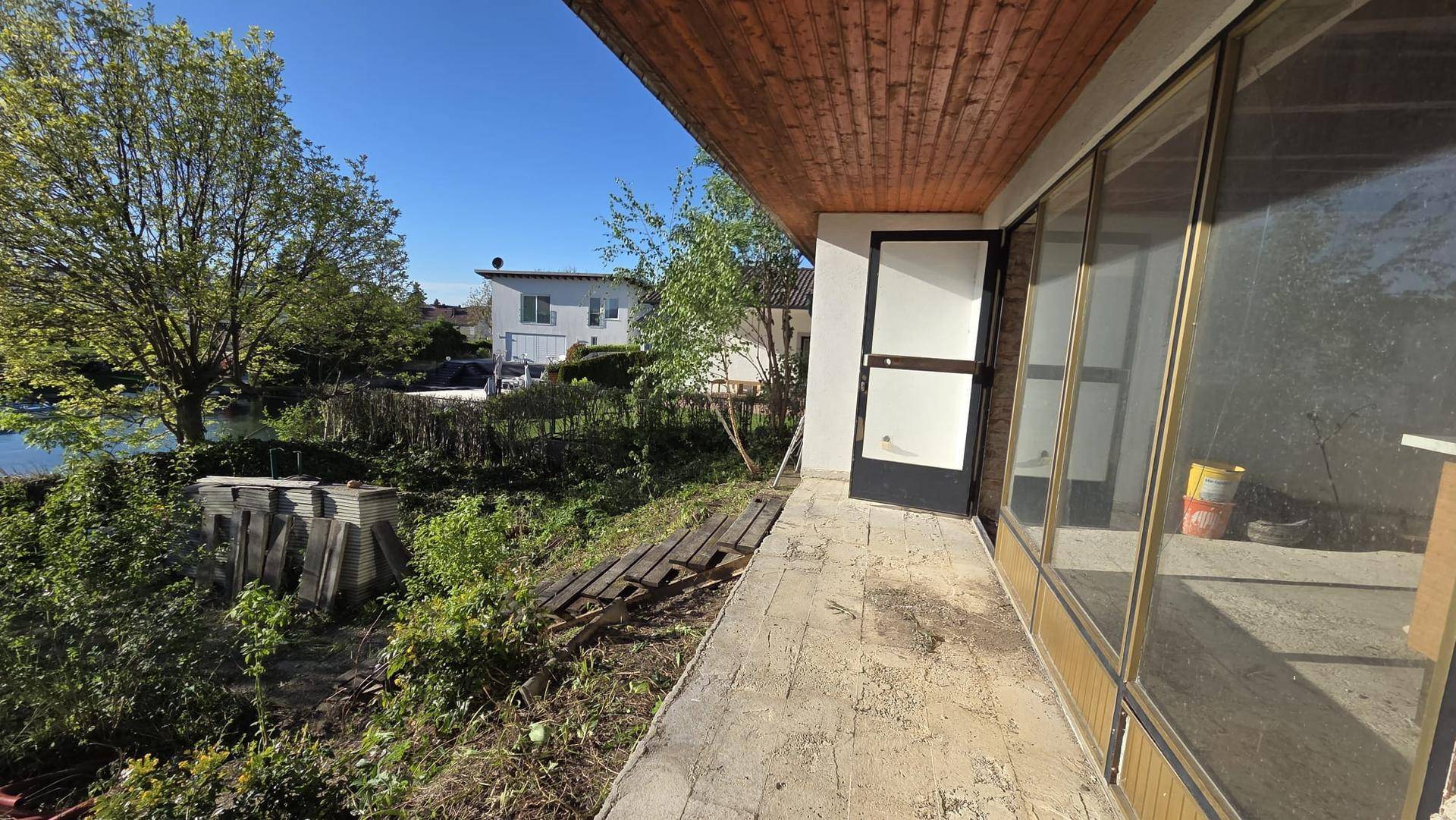 Seitlicher Terrassenbereich des Hauses mit Blick auf den Kanal und die umliegende Natur.