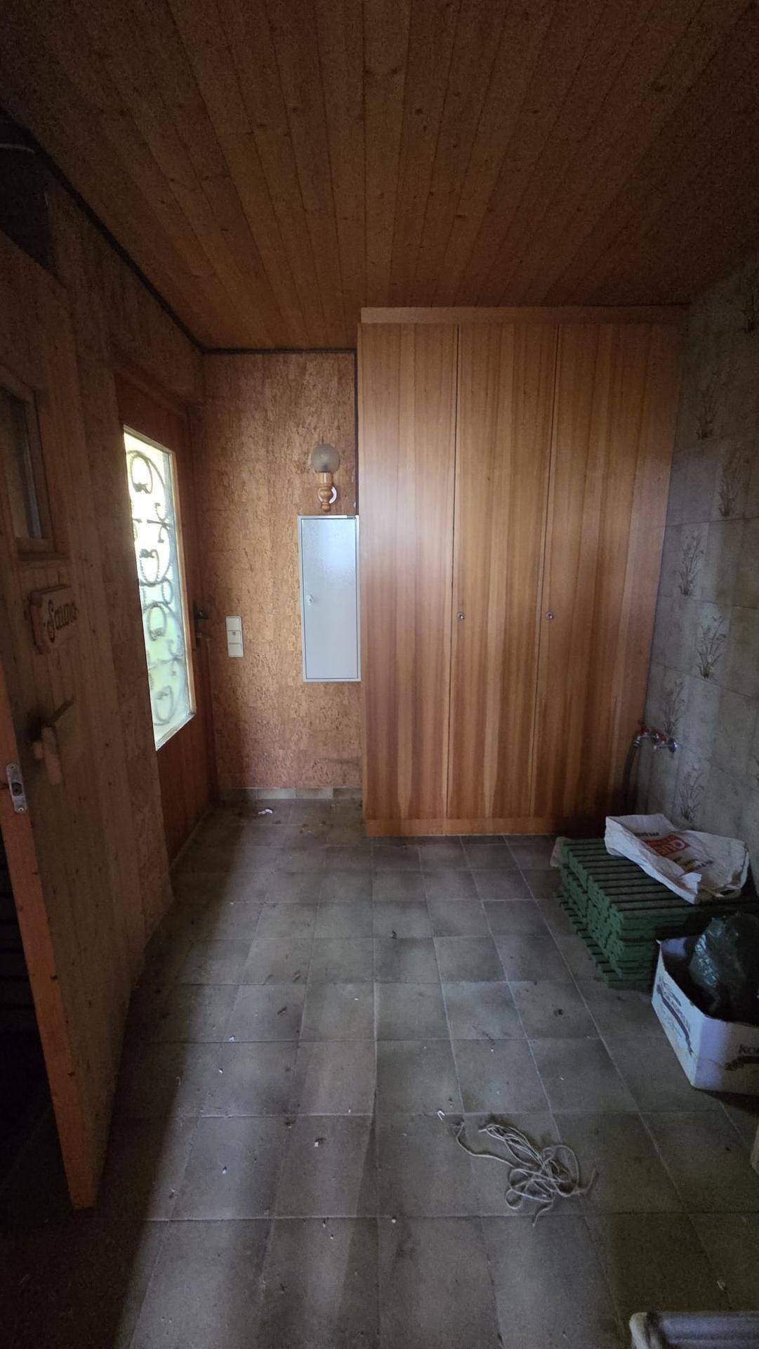 Eingangsbereich mit Holzverkleidung, Fliesenboden und einem integrierten Wandschrank.