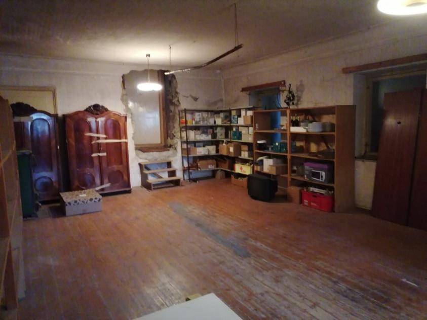 Großer Lagerraum mit Holzboden, Regalen und antiken Schränken, in einem renovierungsbedürftigen Zustand.