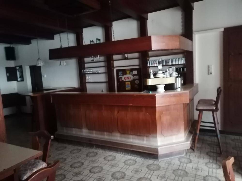 Traditionelle Bar mit Holzelementen, Theke und Hockern, bereit für den Betrieb in einem gemütlichen Ambiente.