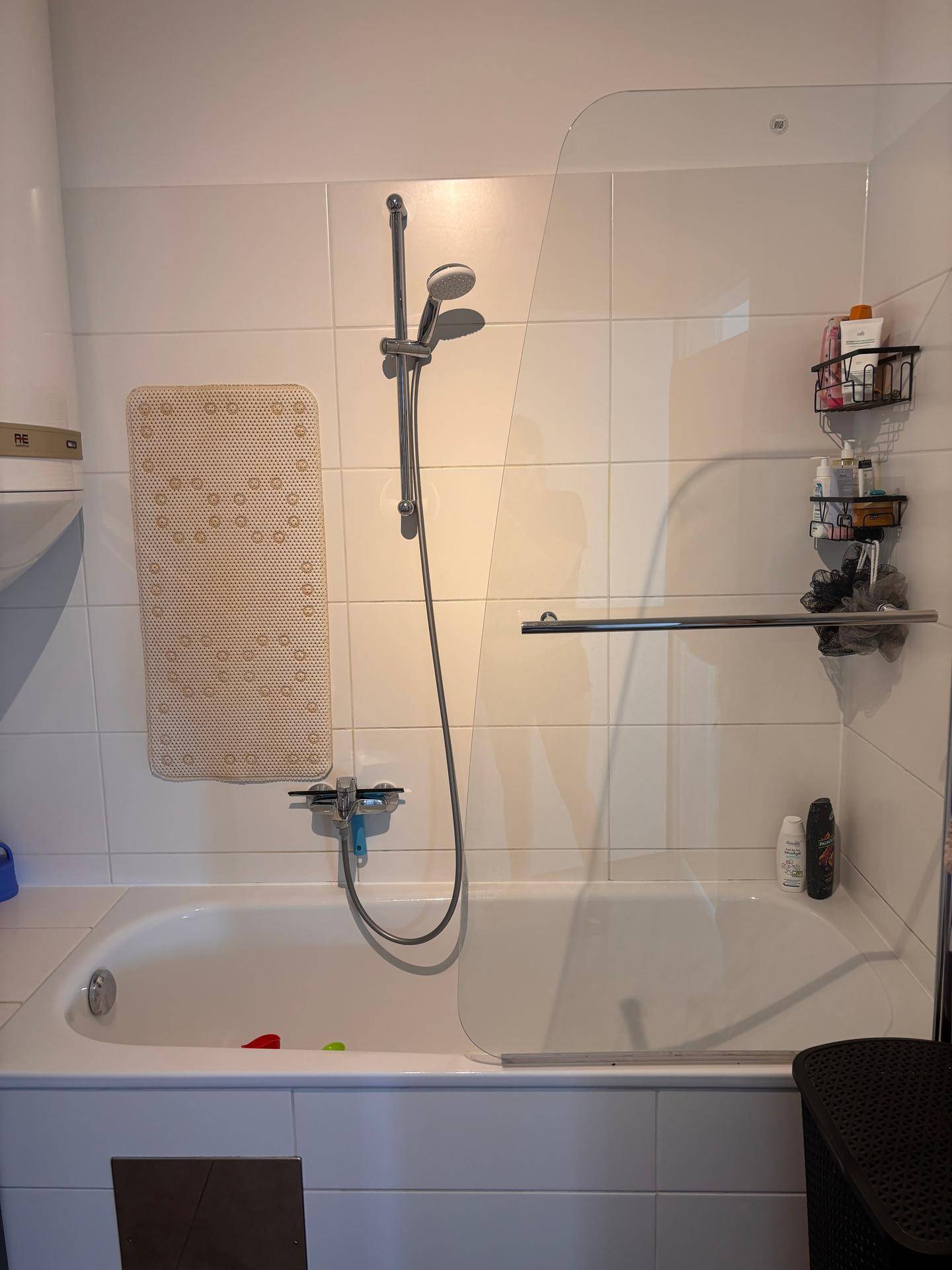 Weiße Badewanne mit Duschfunktion und Glasabtrennung für komfortables Duschen.