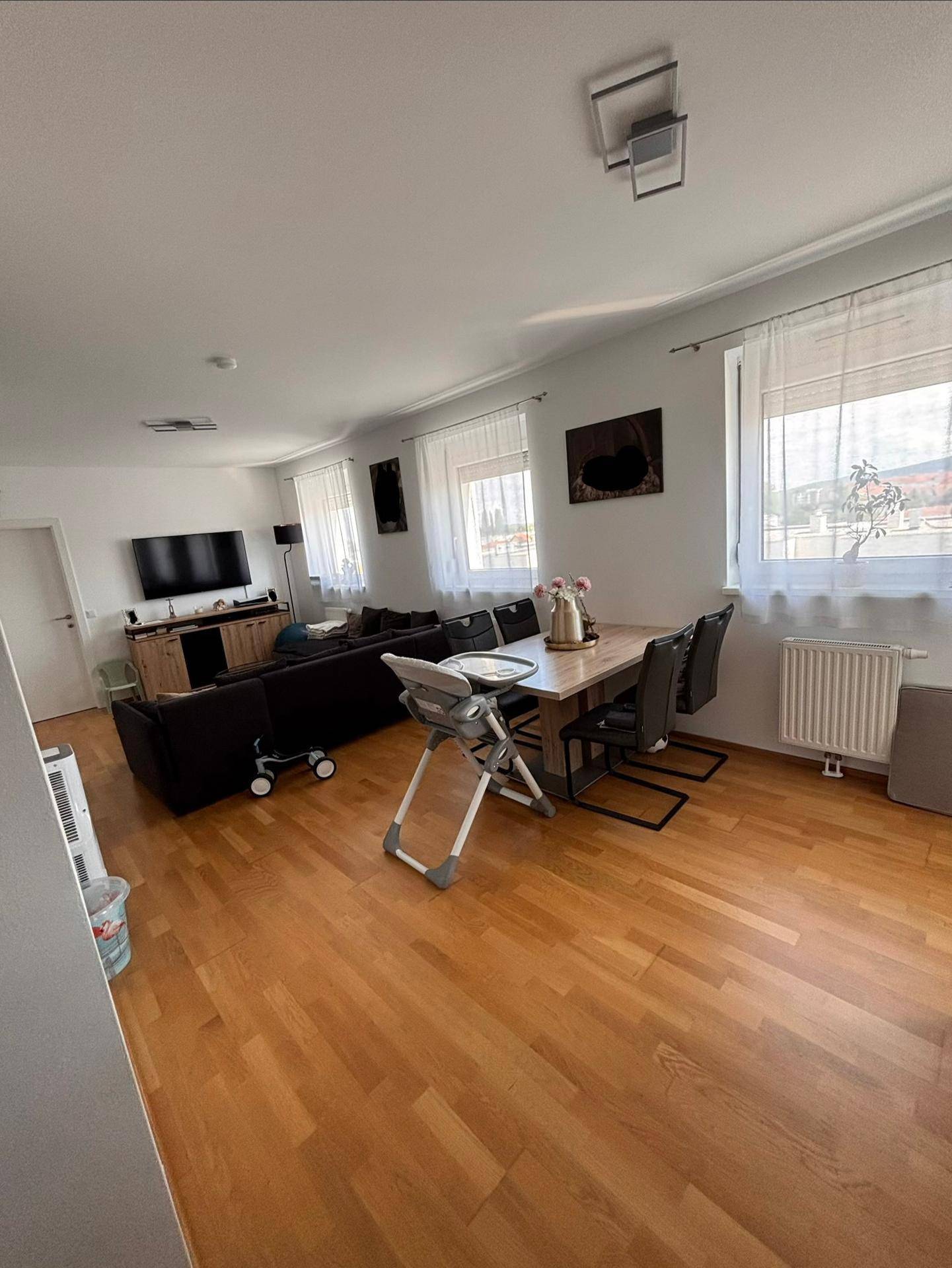 Heller Wohn- und Essbereich mit Holzboden, großem Esstisch und bequemer Sofalandschaft.