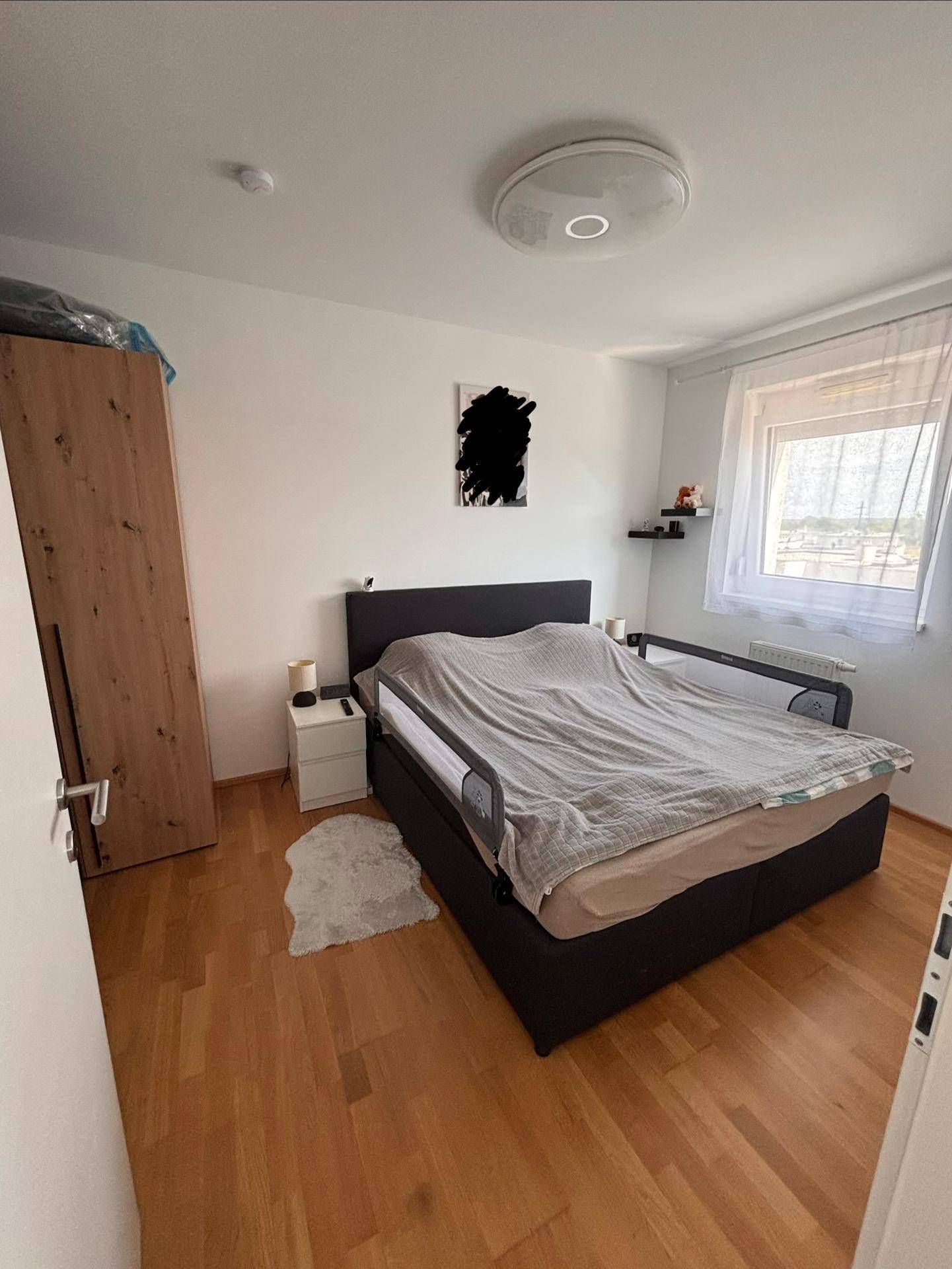 Helles Schlafzimmer mit Holzboden, einem bequemen Bett und einem Kleiderschrank.