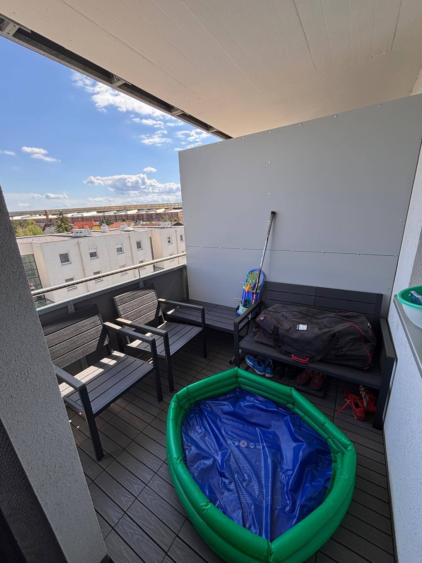 Sonniger Balkon mit Sitzgelegenheiten und Blick auf die umliegenden Gebäude.