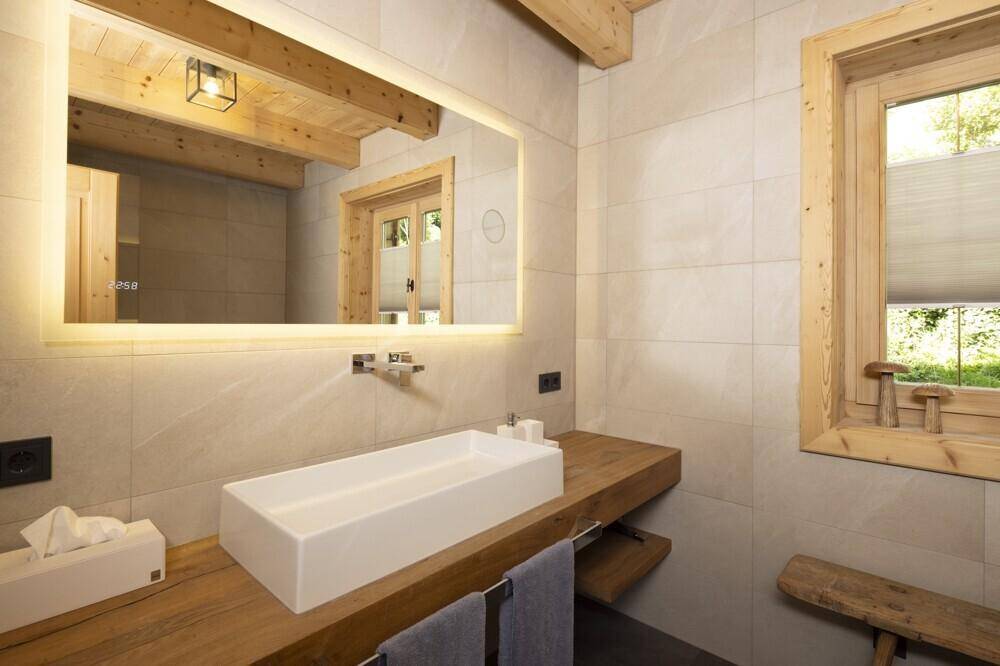 Modernes Badezimmer mit großem Spiegel, Holzwaschtisch und hellen Fliesen.