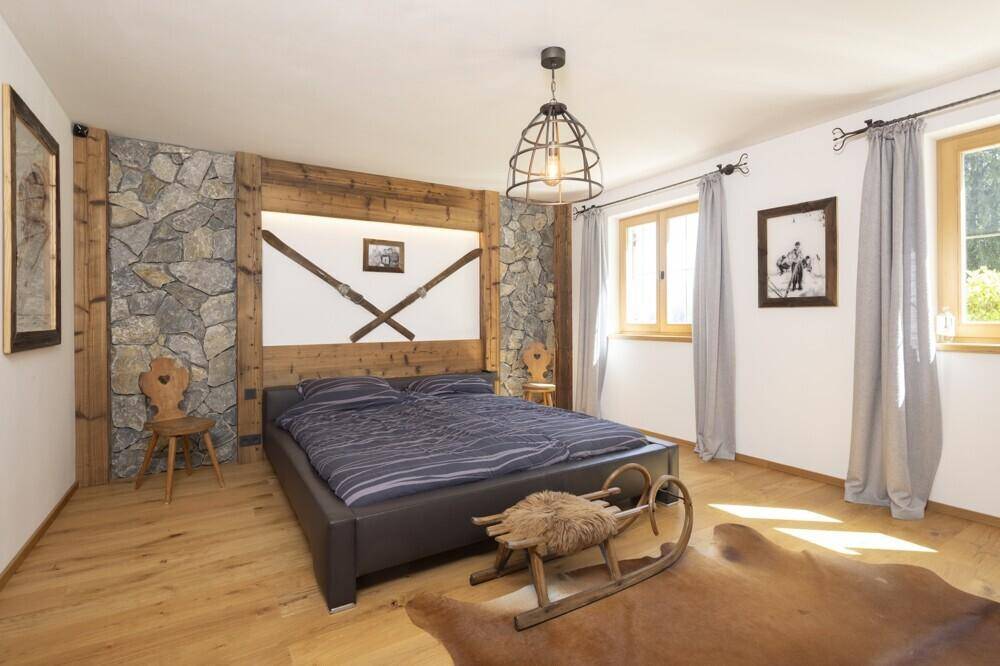 Schlafzimmer im alpinen Stil mit Steinwand, Holzboden und gemütlichem Doppelbett.