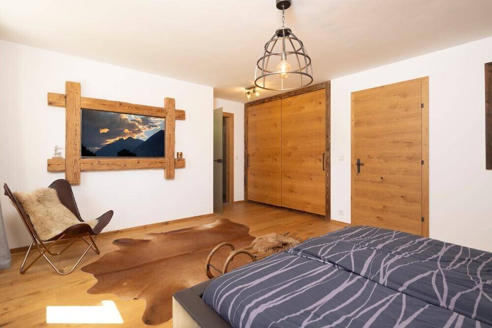 Helles Schlafzimmer mit Holzboden, Einbauschränken und rustikaler Wanddekoration.
