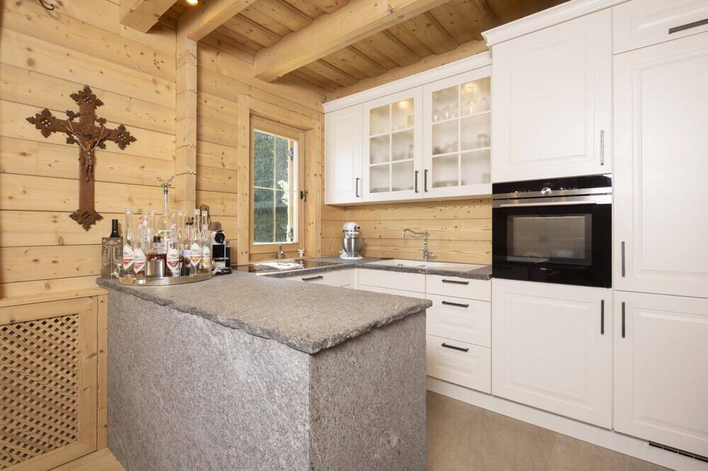 Moderne Küche mit weißen Schränken, Steinarbeitsplatte und Holzwänden im Alpenstil.