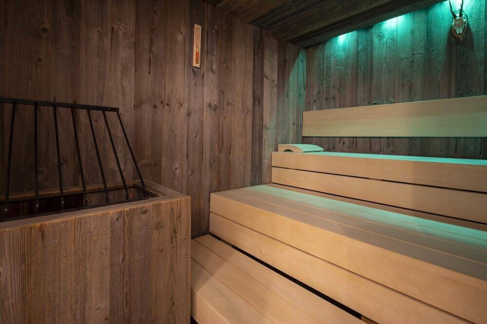 Gemütliche Holzsauna mit Bänken und stimmungsvoller Beleuchtung für Entspannung.
