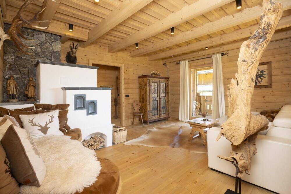 Rustikales Wohnzimmer mit Holzböden, Kachelofen und traditioneller alpiner Dekoration.