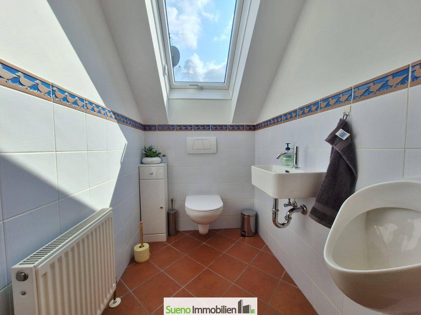 Gäste-WC im Dachgeschoss mit Urinal, wandhängendem WC und Dachfenster.